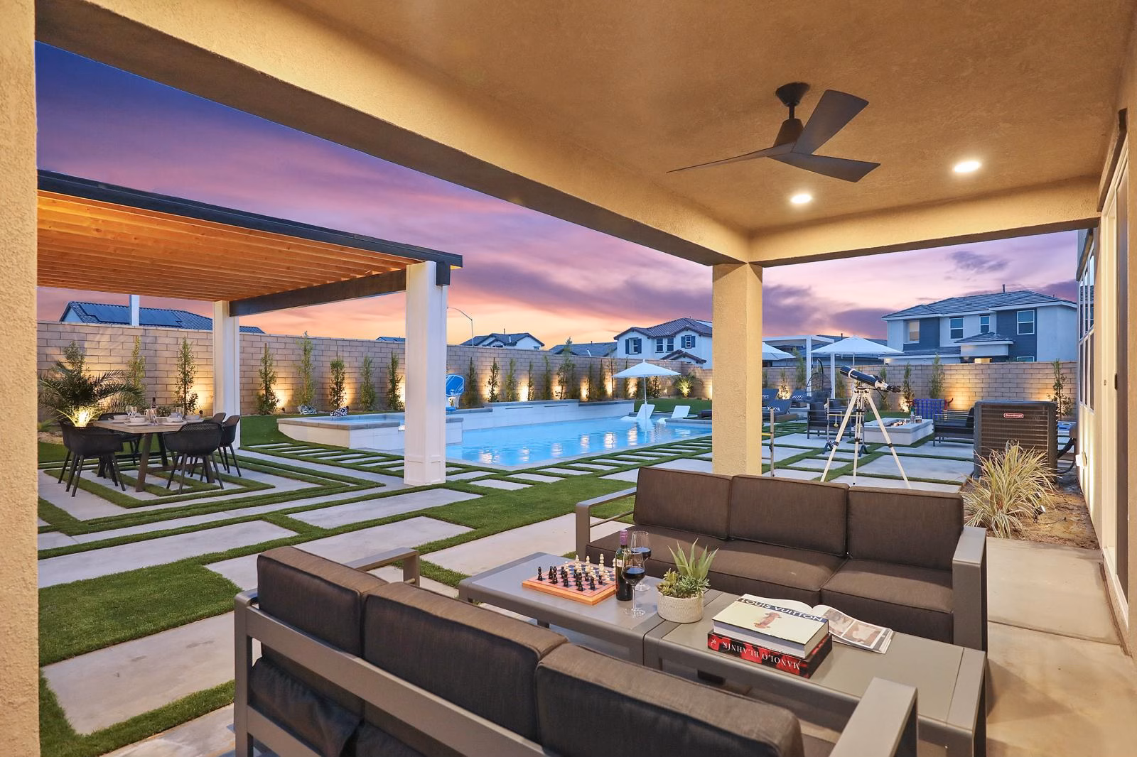 Resort-style pool and outdoor living area at twilight with covered patio, lounge seating, and mountain views - premium amenities like these command top-tier rates but require meticulous maintenance between guest stays